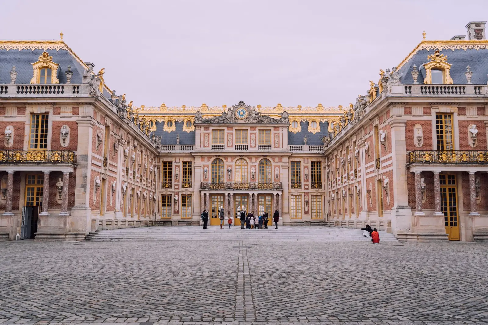 Cour de marbre du château de Versailles, façades de brique et de pierre, pavés au premier plan